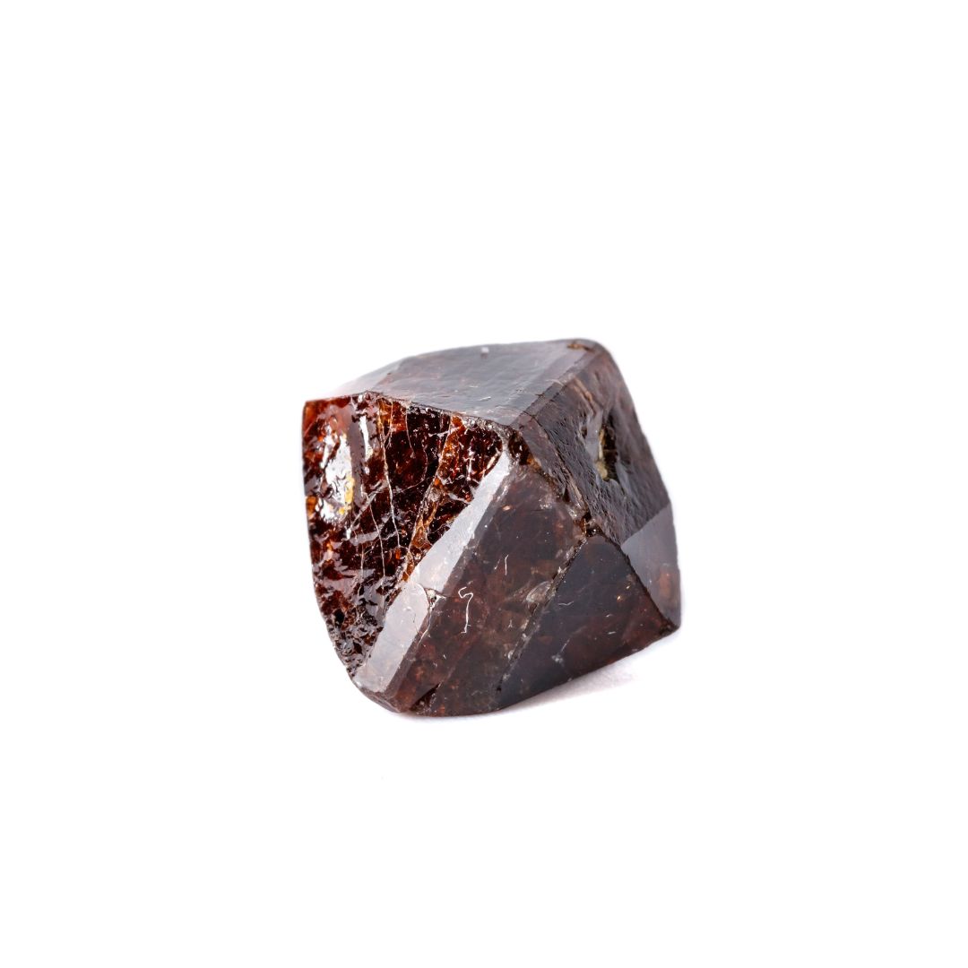 Zircon, a shiny brown/red mineral on a white background. 