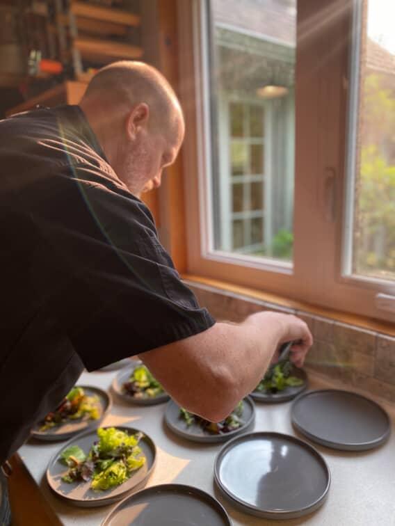 photo of chef adding food to multiple plates
